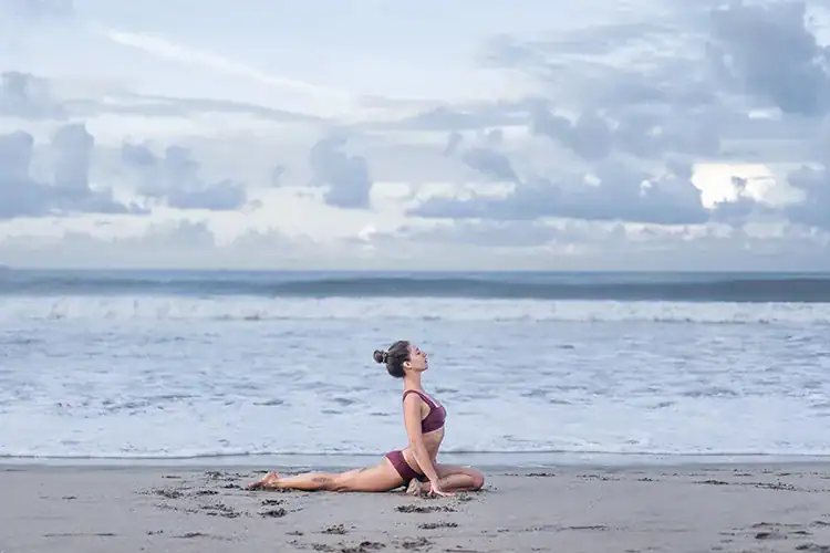 A woman practicing yoga asanas at the beach.