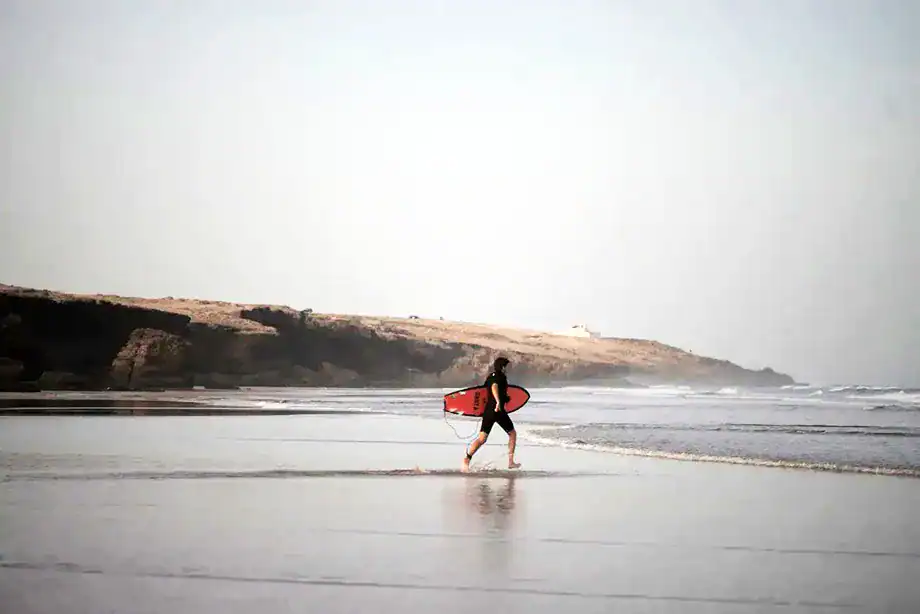 A panoramic view of a surfer entering to the sea in Taghazout.