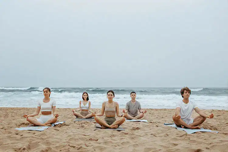 A group of people meditating at the beach in Taghazout.