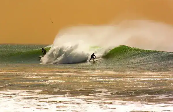 Two surfers riding a wave, surf in Taghazout.