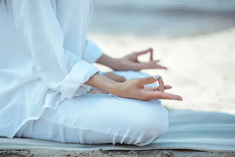 A person dressed in white meditating in Taghazout.